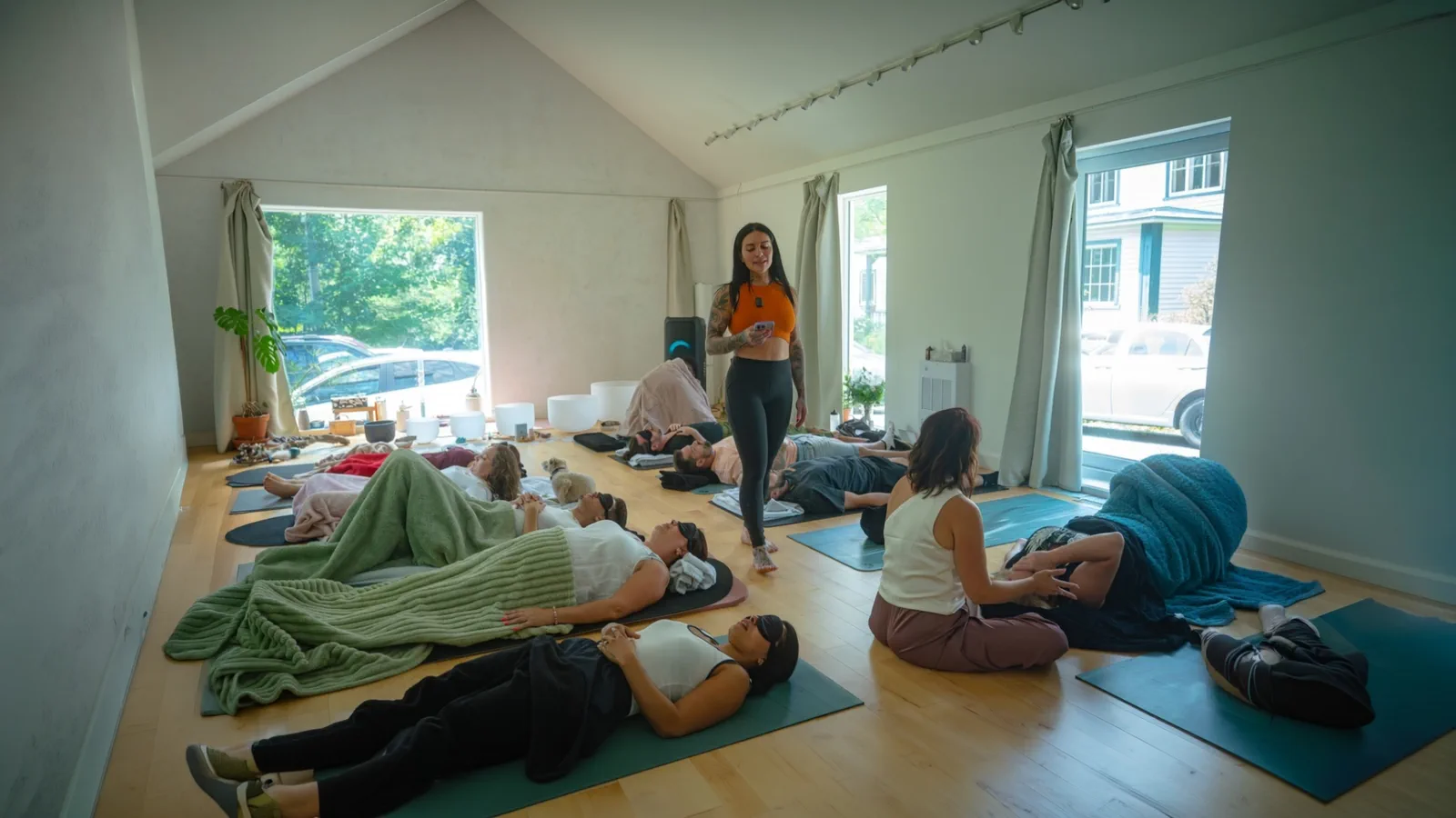 Une activation en groupe : les participant·e·s allongé·e·s sur leur tapis, Krysta debout au centre de la salle